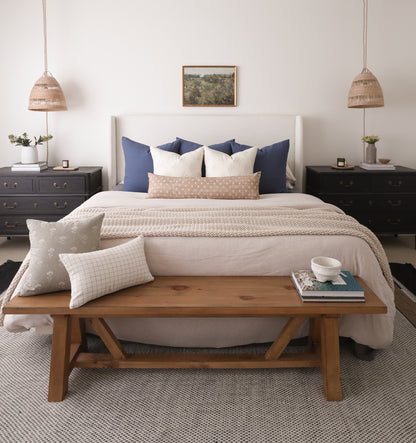 Woven pendant light with natural fiber dome shade and rope suspension in bedroom setting.