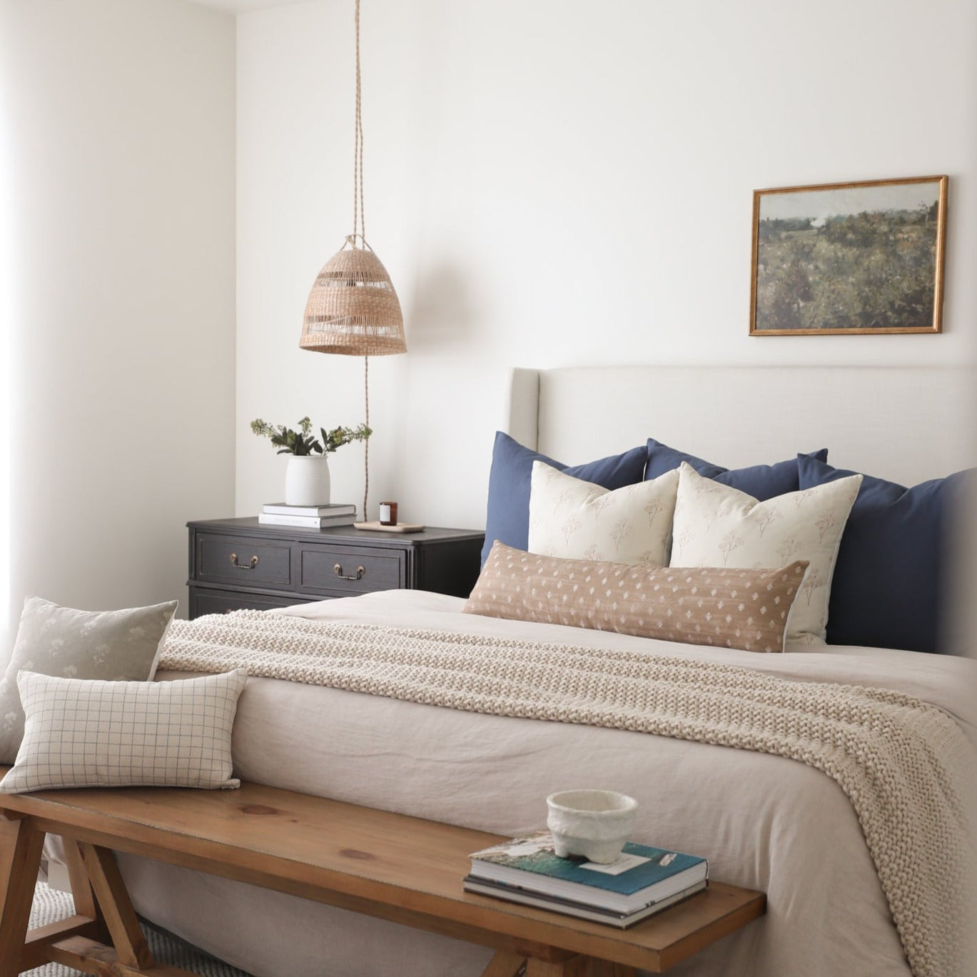 Navy blue and cream decorative pillow set displayed on a bed with matching bedding.