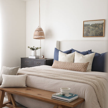 Navy blue and cream decorative pillow set displayed on a bed with matching bedding.