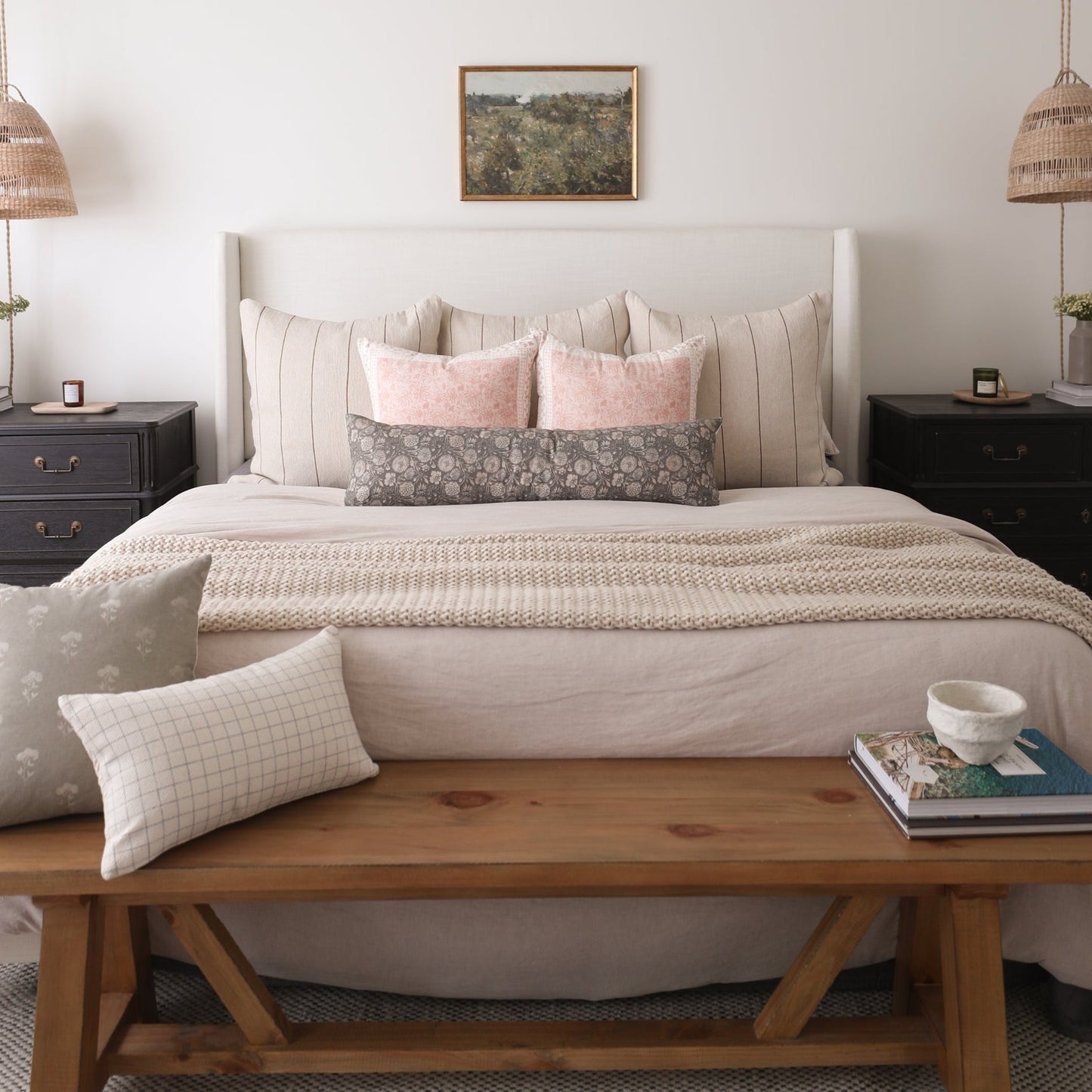 Rectangular lumbar pillow with gray floral pattern displayed on a bed with pink and neutral pillows.