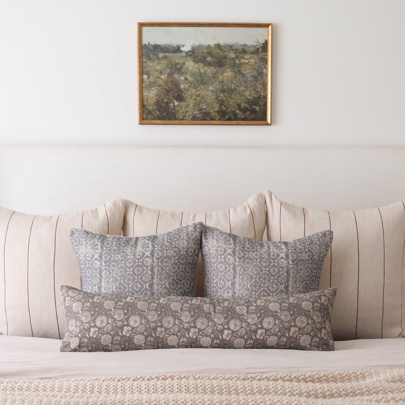 Rectangular lumbar pillow with taupe diamond floral pattern on a thick woven fabric, displayed on a bed.