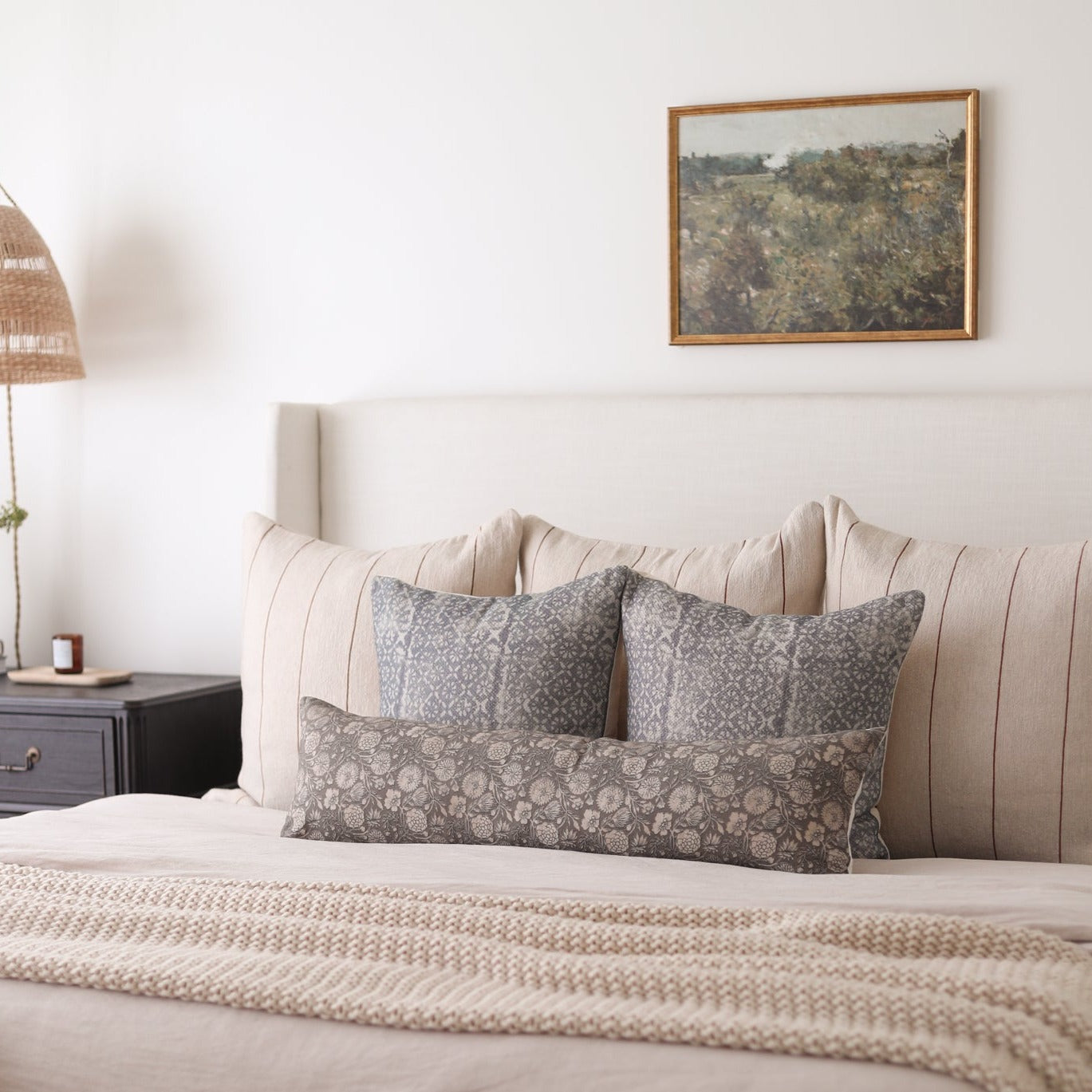 Rectangular lumbar pillow with gray geometric pattern displayed on bed with matching pillows.