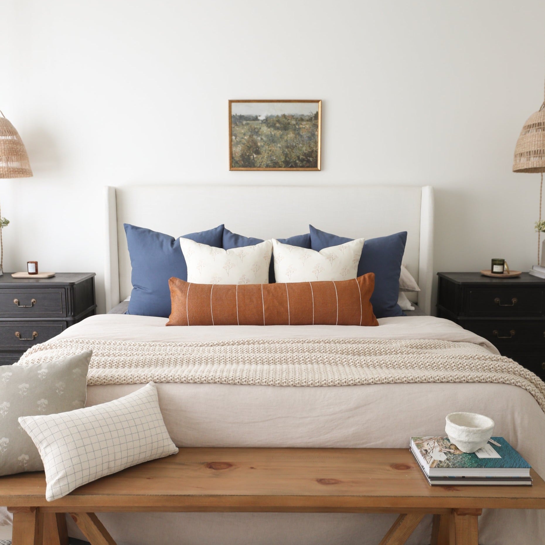 Navy blue rectangular throw pillows arranged on a bed with cream and white accent pillows.