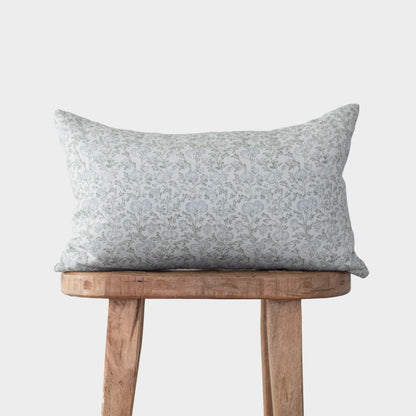Gray and white floral linen pillow with small-scale botanical print displayed on wooden stool.