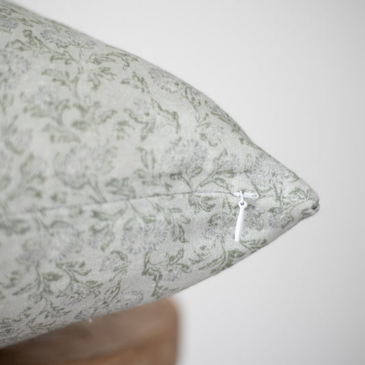 Cream linen pillow with sage green damask pattern and white zipper detail.