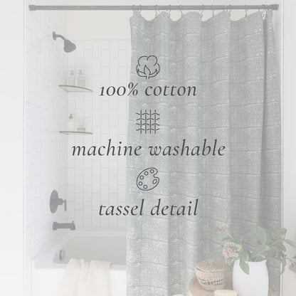 Gray damask patterned cotton shower curtain with tassel details, hung in a bathroom with tub and fixtures visible.