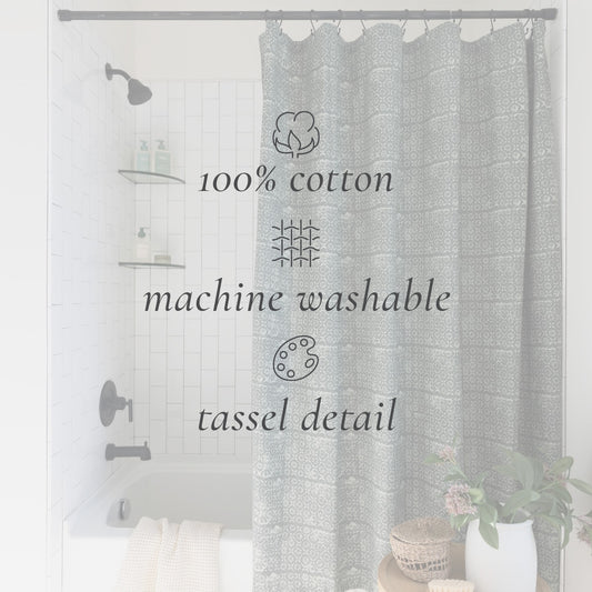 Gray damask patterned cotton shower curtain with tassel details, hung in a bathroom with tub and fixtures visible.
