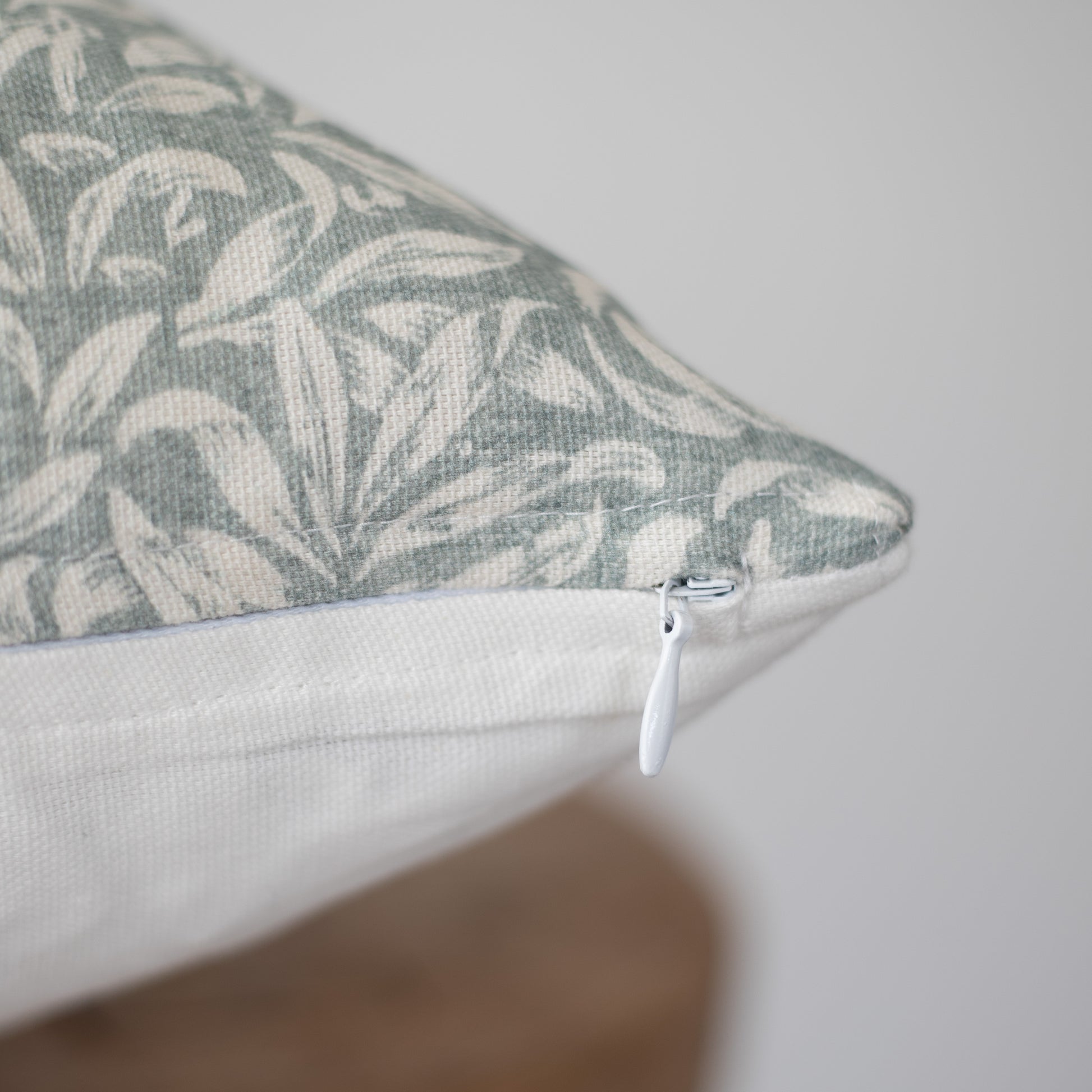 Rectangular pillow with gray and cream botanical leaf pattern and white zipper closure.