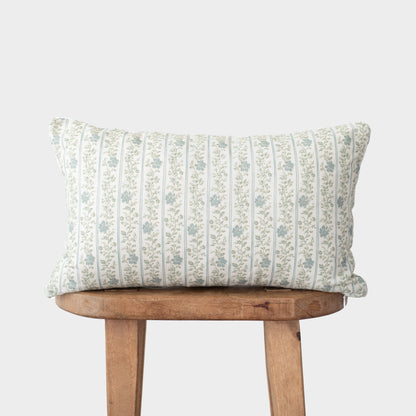 Cream-colored pillow with blue vertical striped floral pattern on wooden stool.