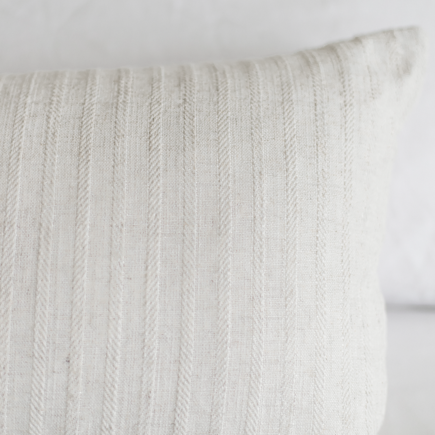 Cream-colored pillow with vertical cable knit texture pattern.