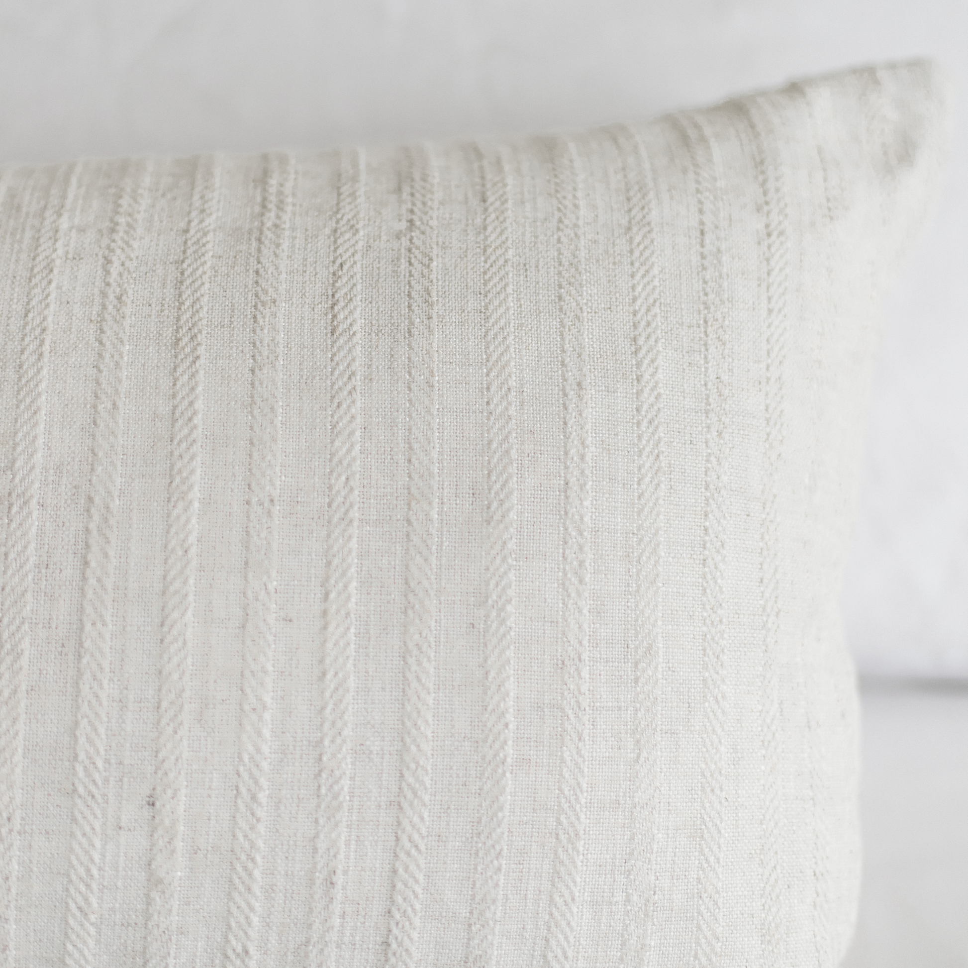 Cream-colored pillow with vertical cable knit texture pattern.