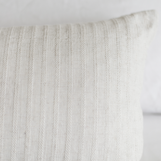 Cream-colored pillow with vertical cable knit texture pattern.