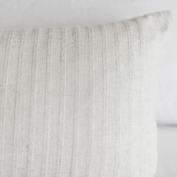 Cream-colored pillow with vertical cable knit texture pattern.