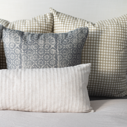Three decorative pillows with textured fabrics: white ribbed, gray patterned, and beige gingham.