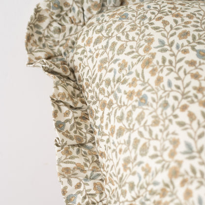 Cream pillow with tan and blue floral leaf pattern and ruffled edge detail.