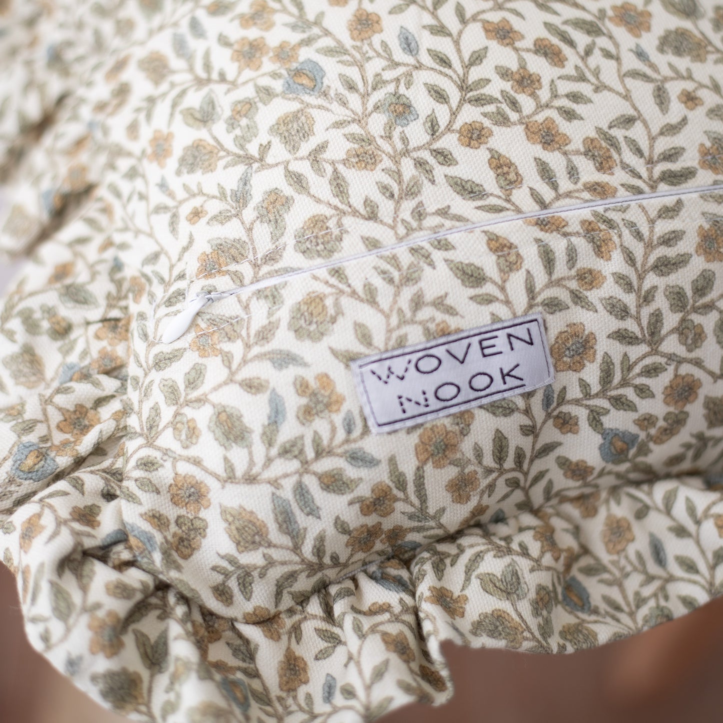 Cream-colored fabric with tan and gray floral leaf pattern and ruffled edge detail.