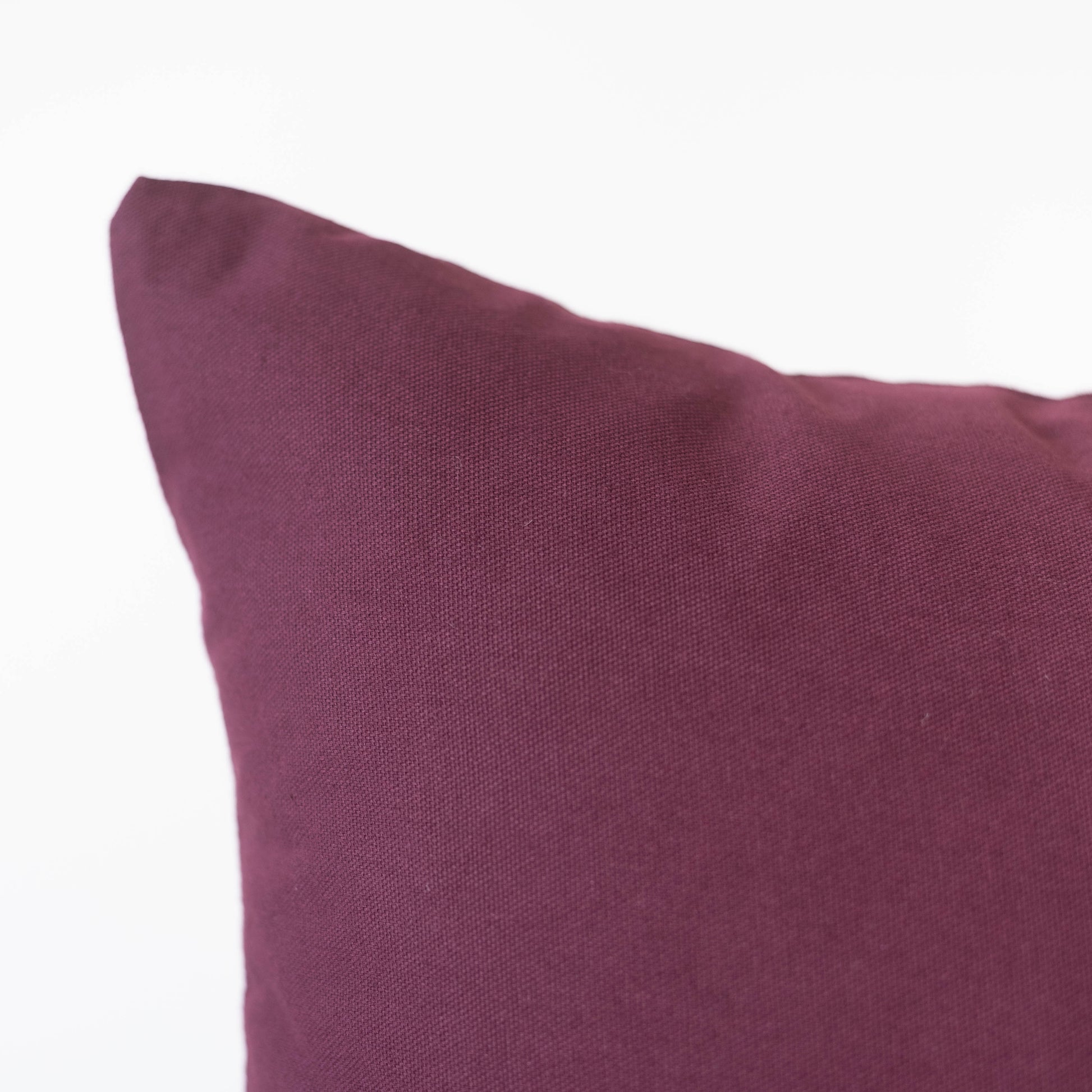 Merlot-colored pillow with textured fabric and a soft, filled form.
