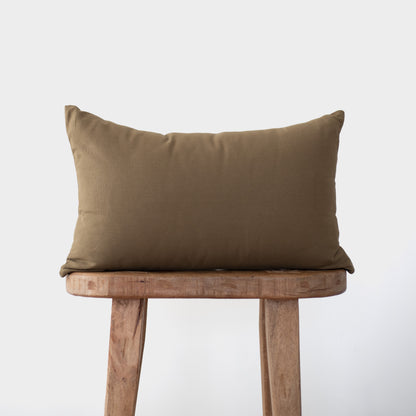 Rectangular moss-colored lumbar pillow with solid weave fabric displayed on wooden chair.