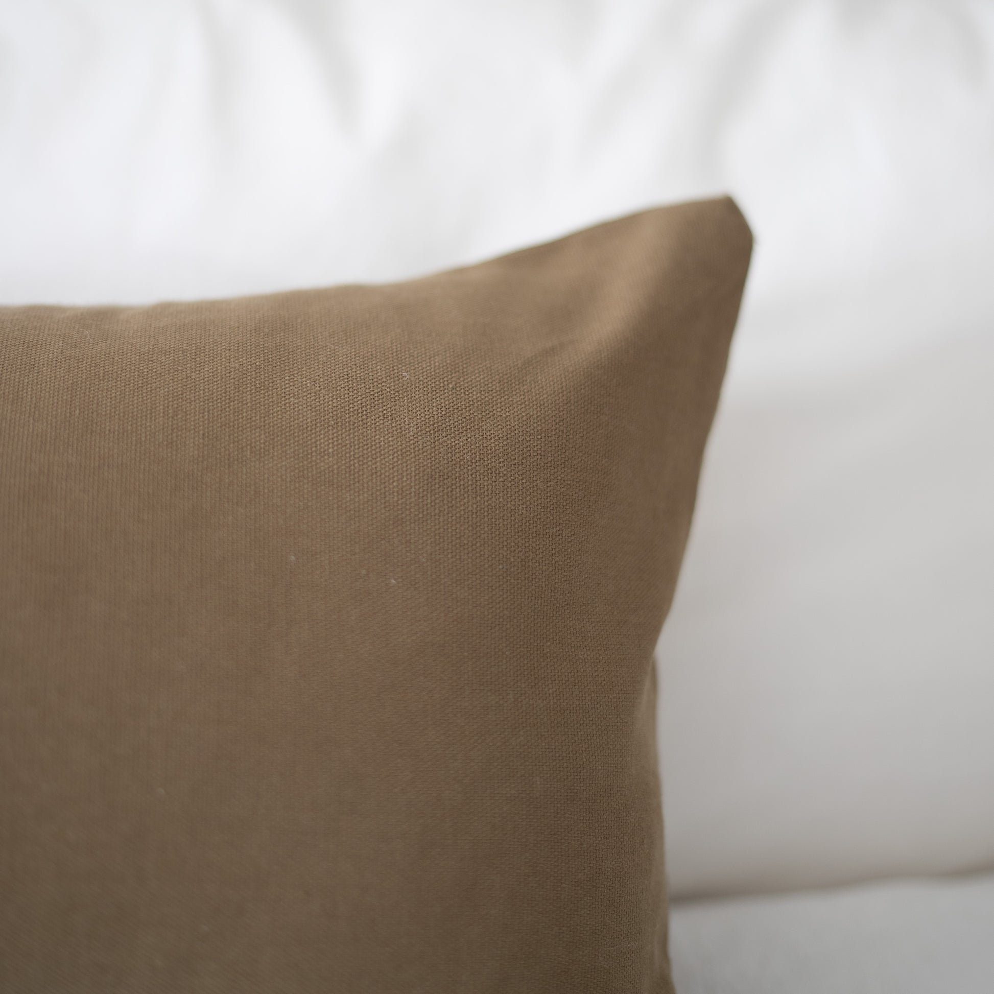Tan lumbar pillow with woven texture against white background.