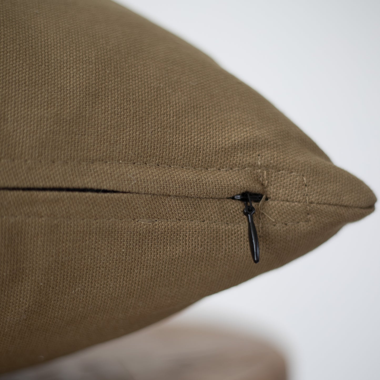 Moss-green lumbar pillow with textured fabric and black zippered closure detail.