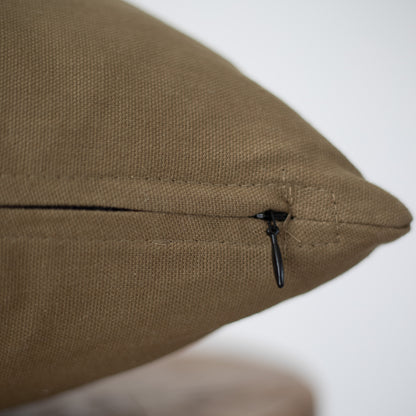 Moss-green lumbar pillow with textured fabric and black zippered closure detail.