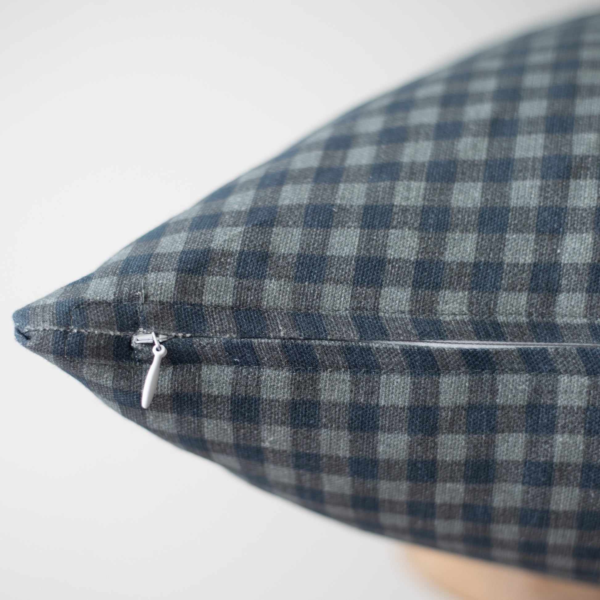 Navy and white gingham patterned pillow with zipper closure detail visible on seam.