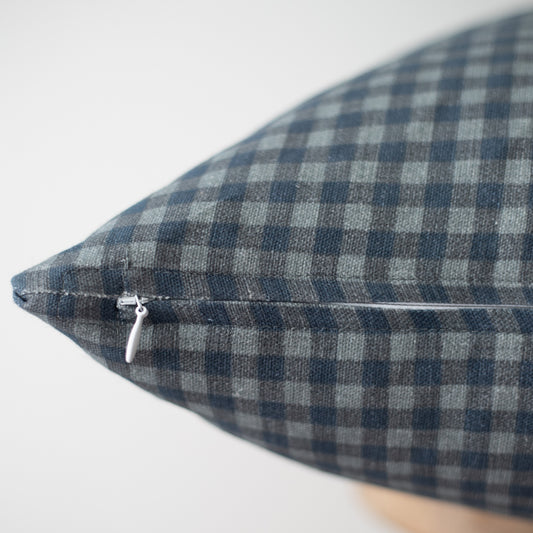 Navy and white gingham patterned pillow with zipper closure detail visible on seam.