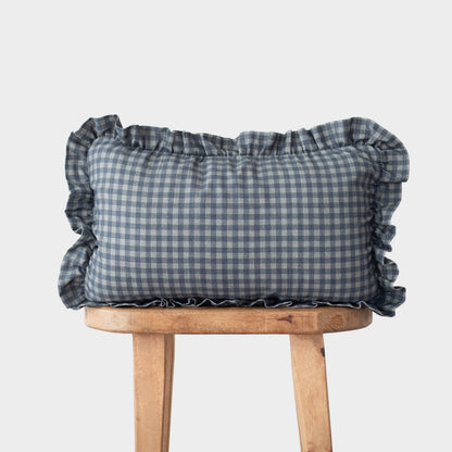 Navy gingham pillow with ruffled edges on all sides, displayed on wooden stool.