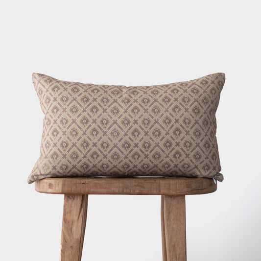 Noa pillow with geometric diamond pattern in taupe and cream tones on wooden stool.