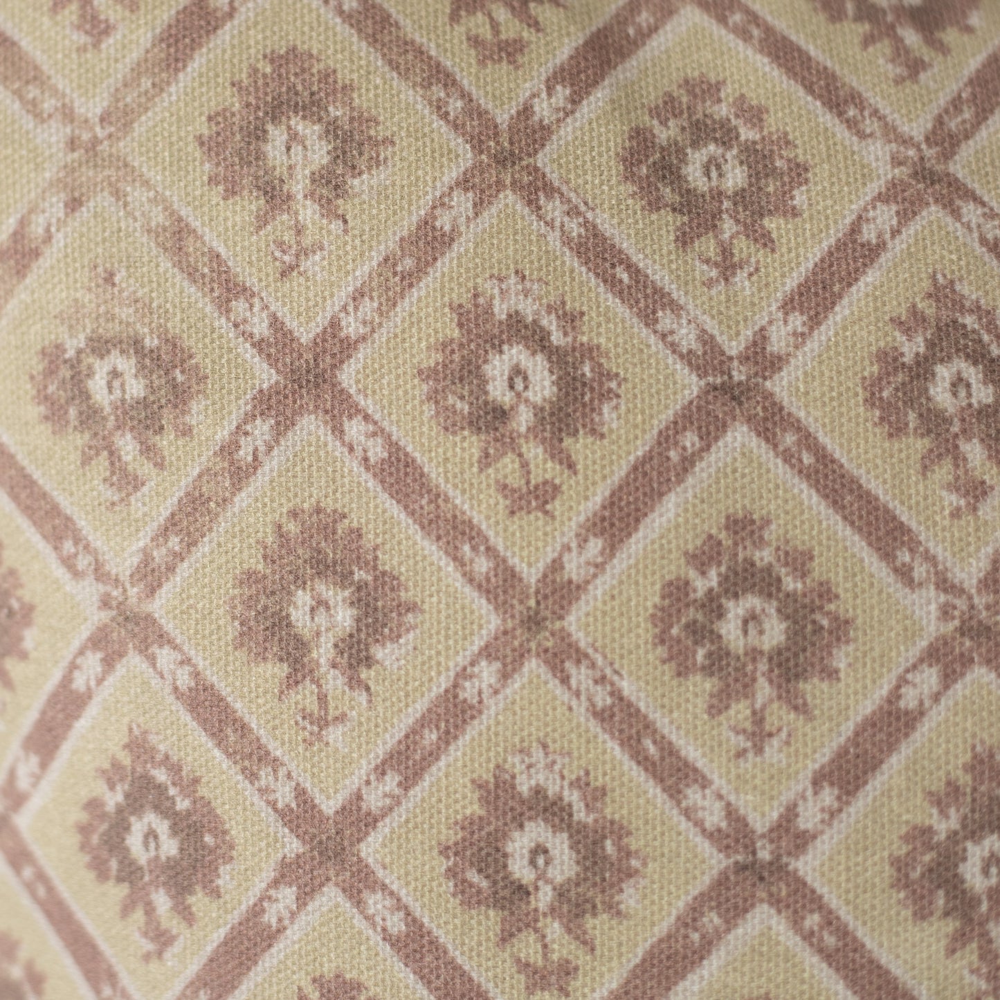Beige and mauve textile with geometric diamond pattern containing floral motifs in a woven weave.