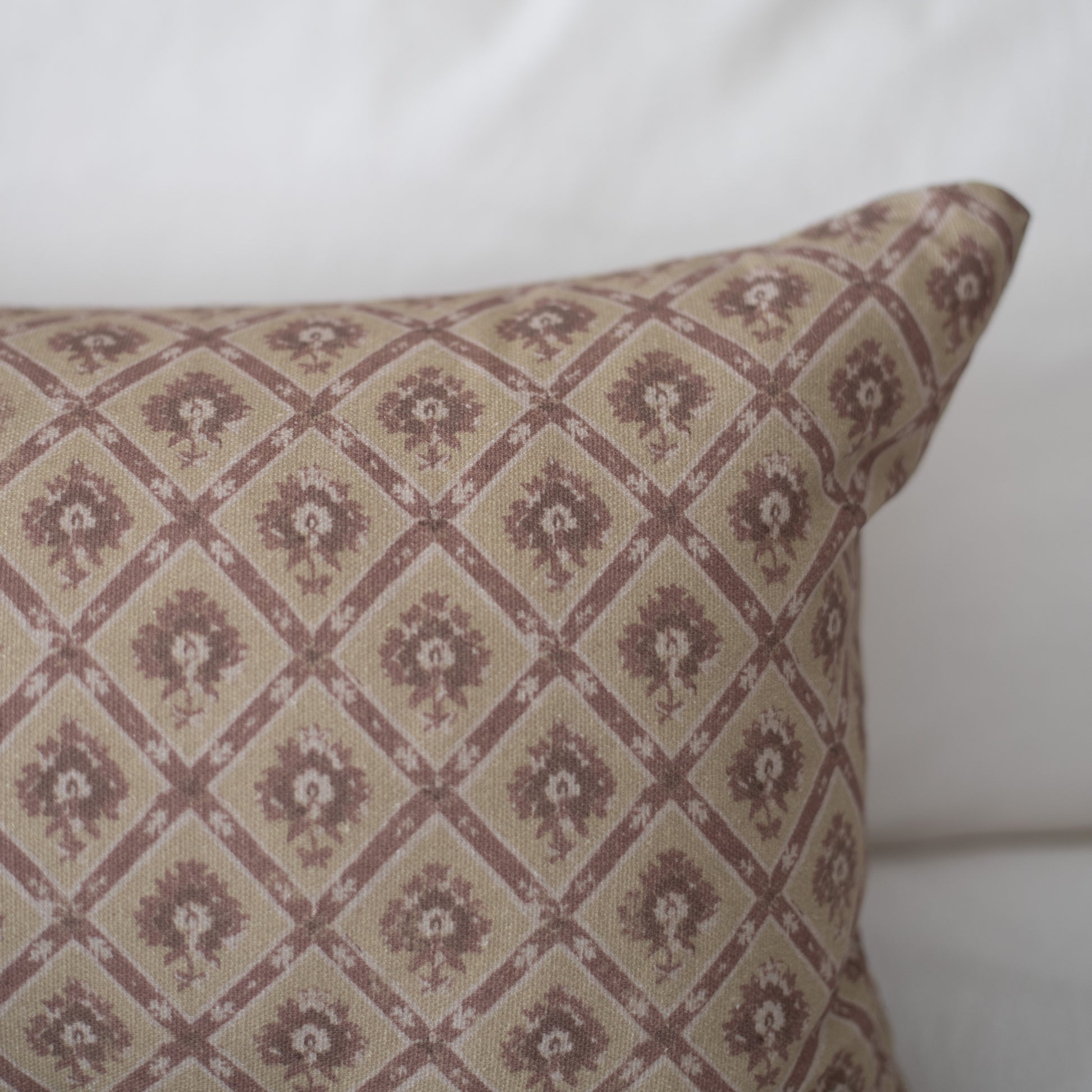 Rectangular pillow with taupe and mauve geometric diamond pattern containing floral motifs throughout.