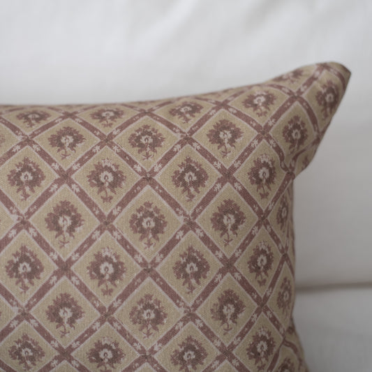 Rectangular pillow with taupe and mauve geometric diamond pattern containing floral motifs throughout.
