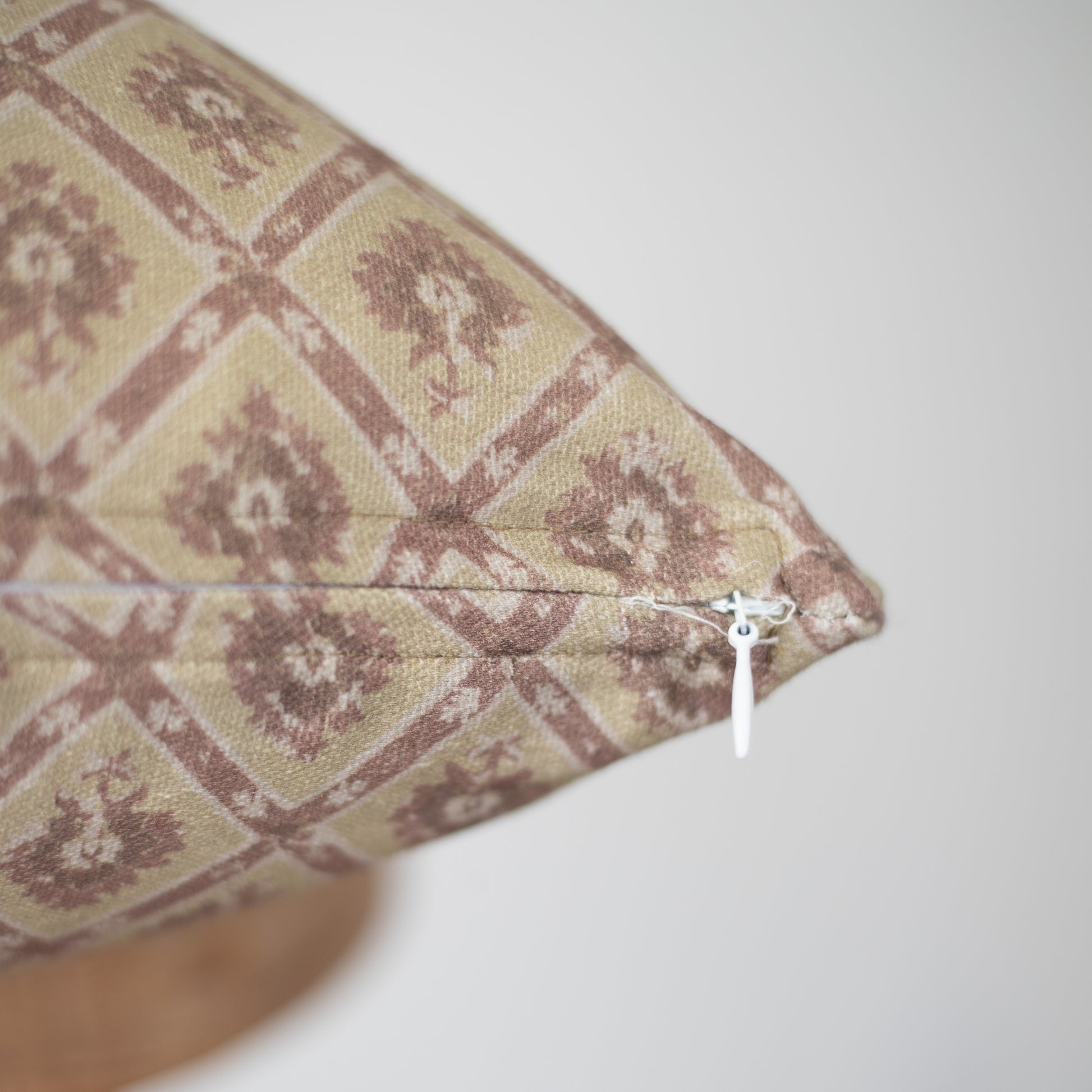 Rectangular pillow with cream and mauve geometric tile pattern, white zipper closure visible on side.