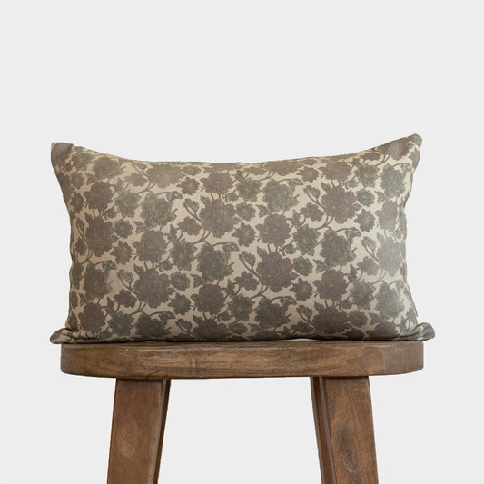 Rectangular lumbar pillow with gray floral damask pattern on cream background, displayed on wooden stool.