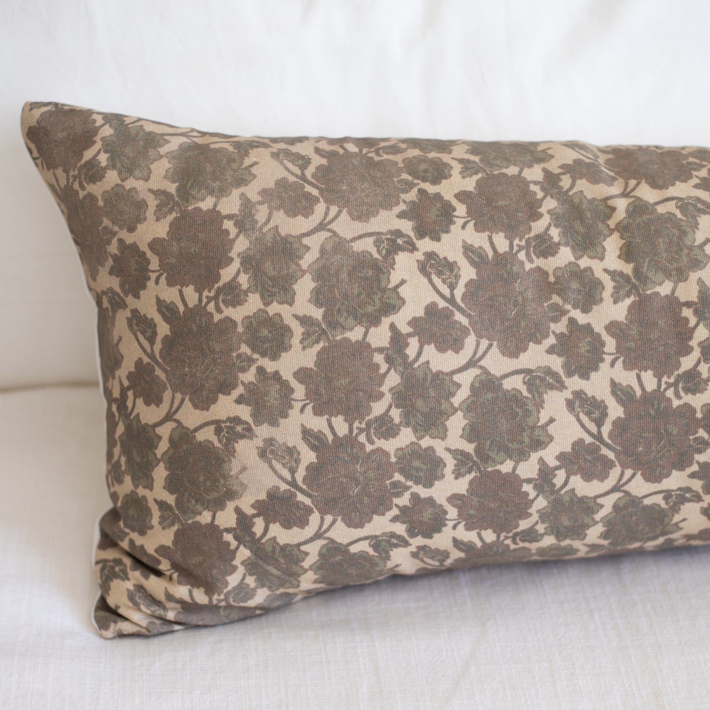 Rectangular lumbar pillow with gray floral pattern on cream background, displayed at an angle.