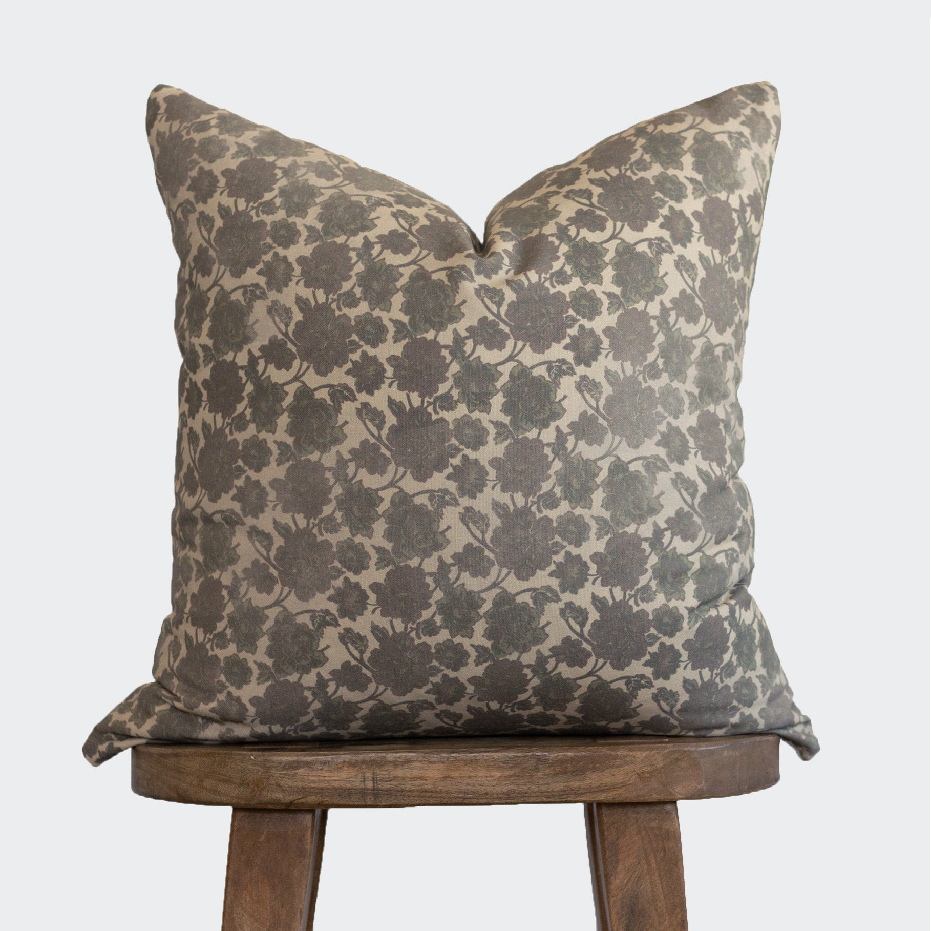 Taupe and cream floral damask patterned pillow with envelope closure displayed on wooden stool.
