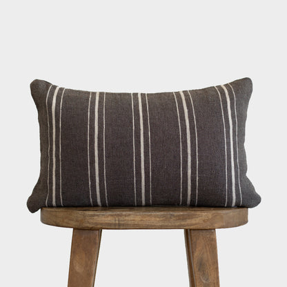 Charcoal lumbar pillow with white vertical stripes on wooden stool.
