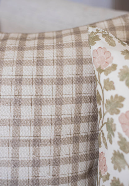 Beige and white checked cotton fabric with a floral patterned pillow showing pink flowers and green leaves.