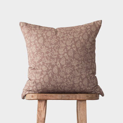 Taupe damask patterned pillow with cream floral motif displayed on wooden stool.