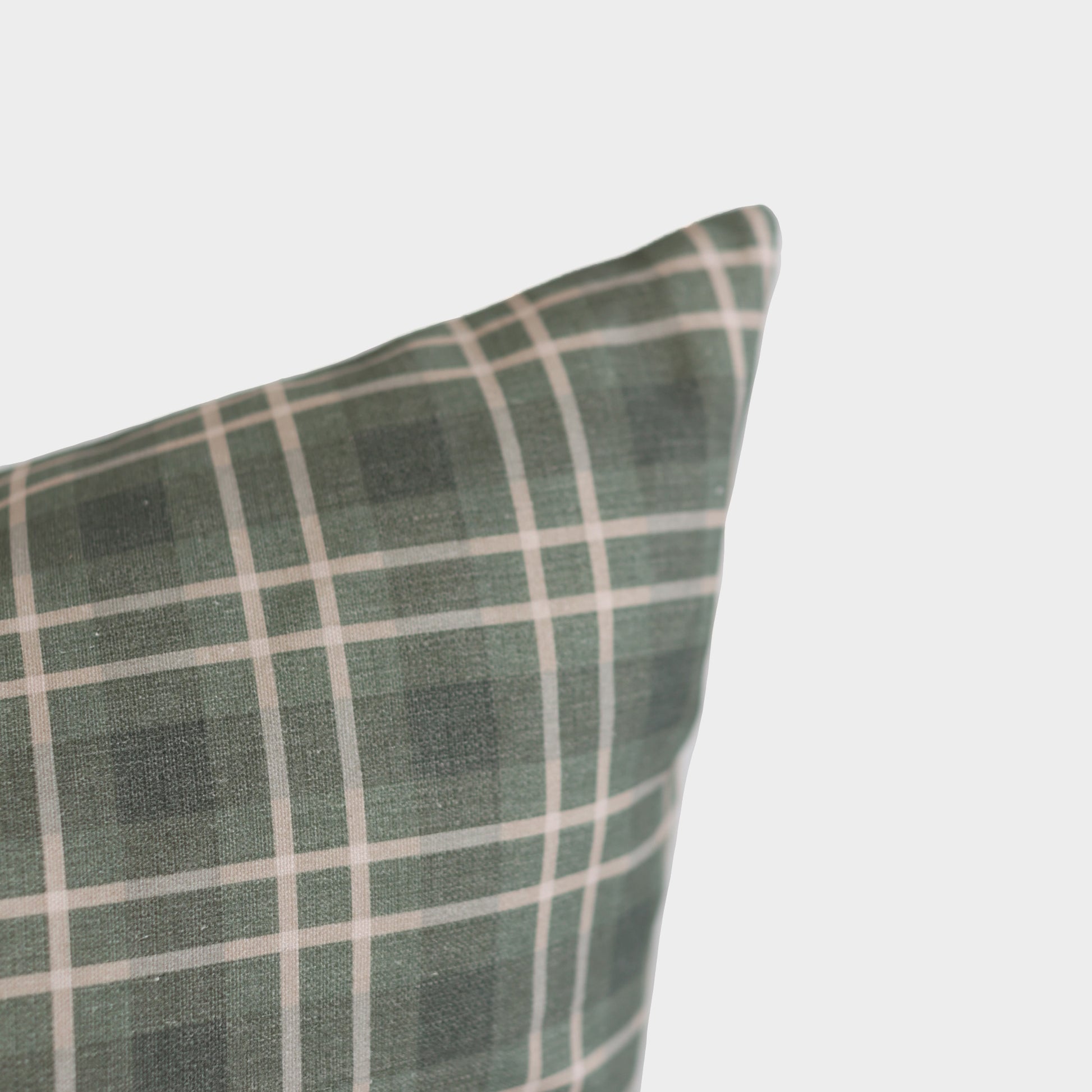 Green and white plaid pillow with grid pattern displayed at an angle against a light background.