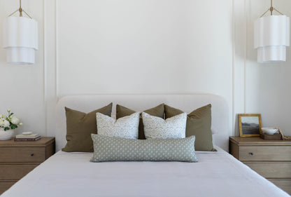 Set of four king pillow covers in olive green and light blue patterned fabrics on a white bed.