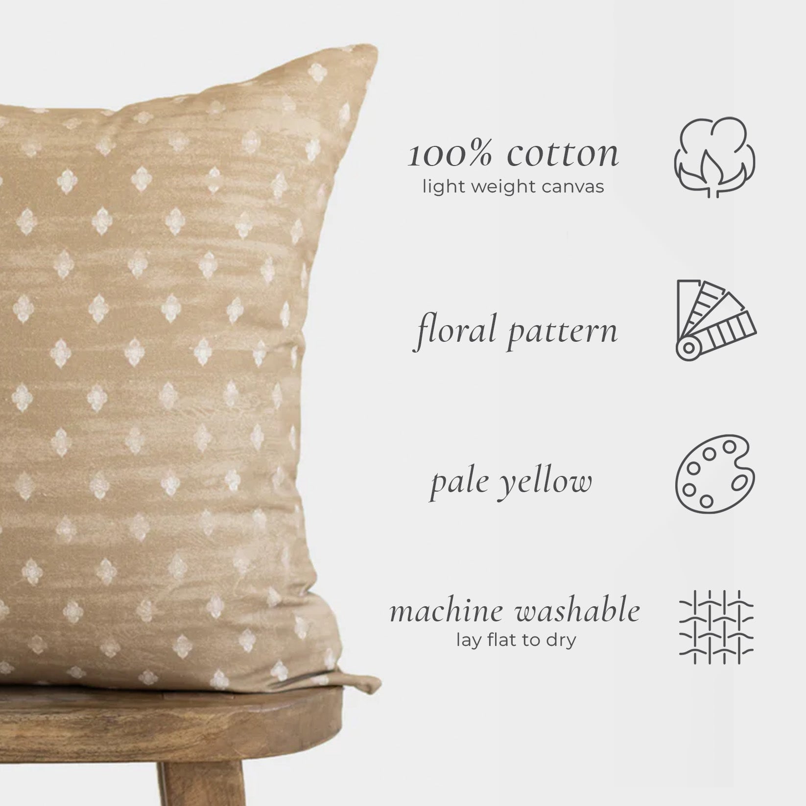 Pale yellow cotton throw pillow with white floral diamond pattern, displayed on wooden chair.