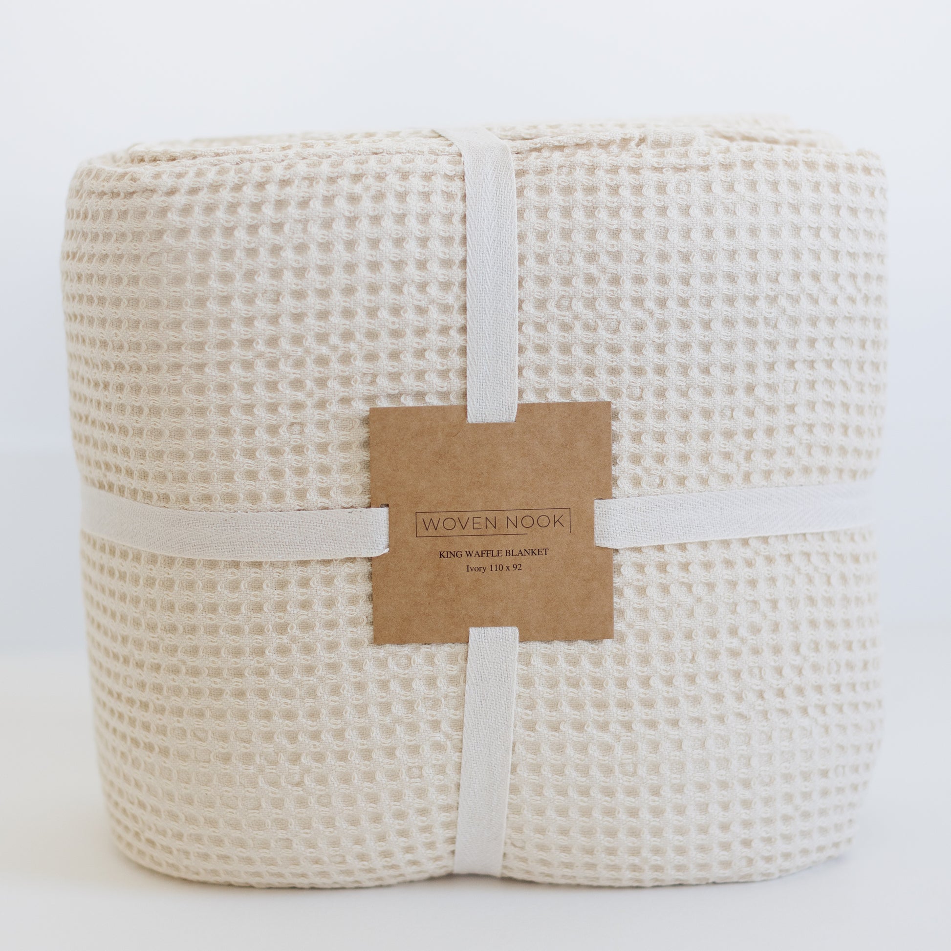 Ivory waffle blanket rolled and tied with cream ribbon and branded paper label.