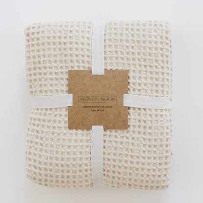 Ivory waffle blanket rolled and tied with white ribbon and kraft paper band label.