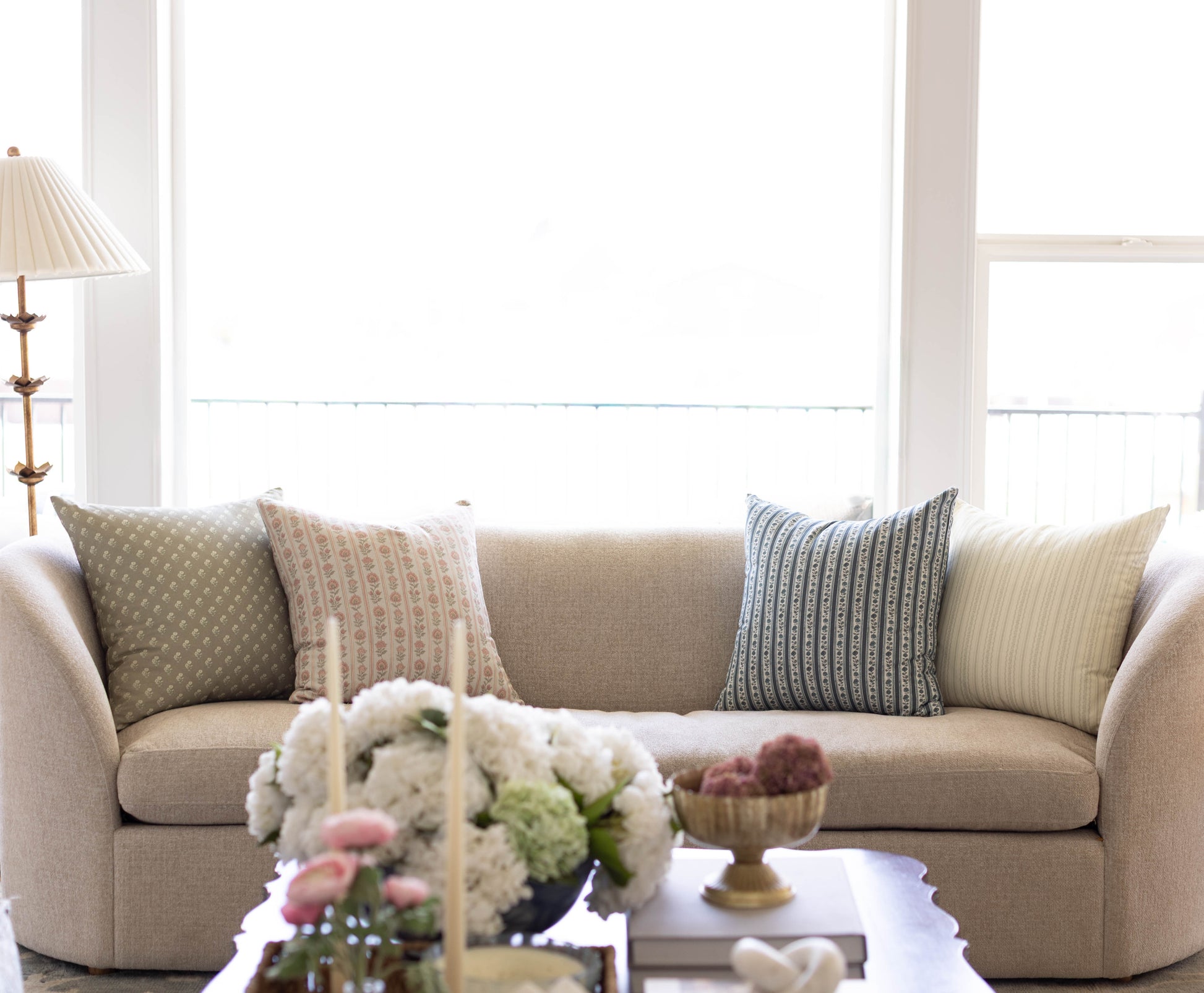 Four decorative pillows in various patterns including geometric, striped, and textured designs in neutral and blue tones arra