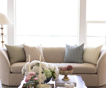Four decorative pillows in various patterns including geometric, striped, and textured designs in neutral and blue tones arra