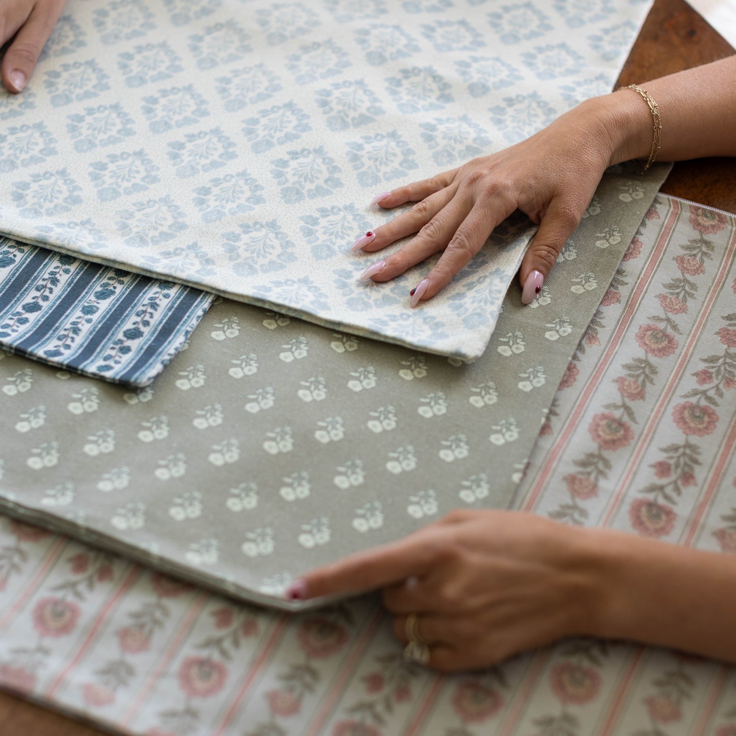 Three fabric swatches with floral and striped patterns in blue, gray, and pink tones displayed flat.