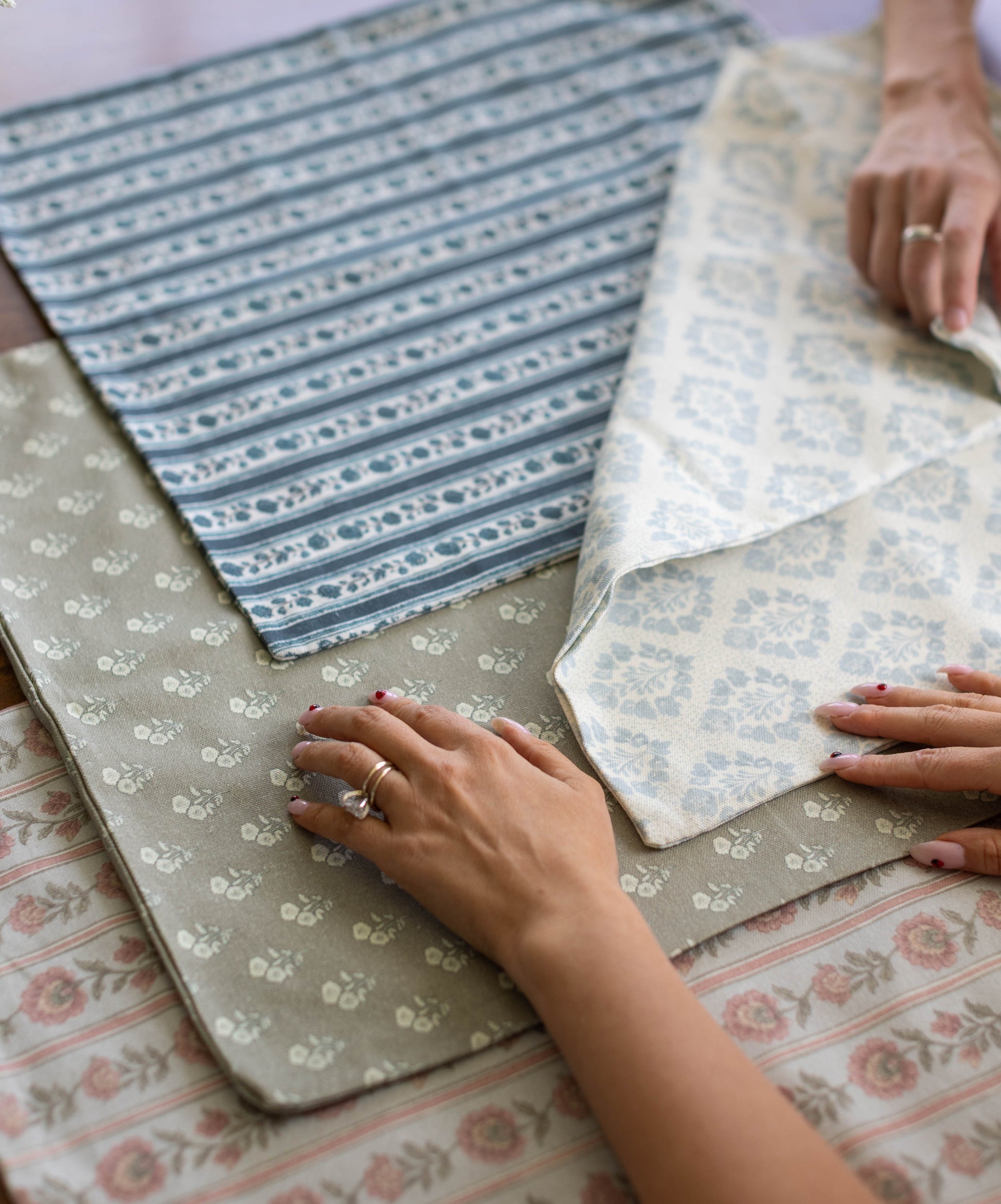 Collection of fabric swatches with floral and striped patterns in blue, cream, and neutral tones displayed flat.