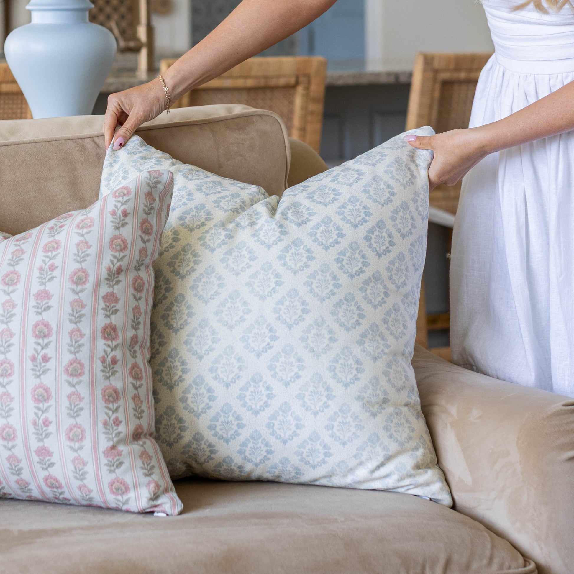 Decorative pillows with damask and floral patterns displayed on a beige sofa.