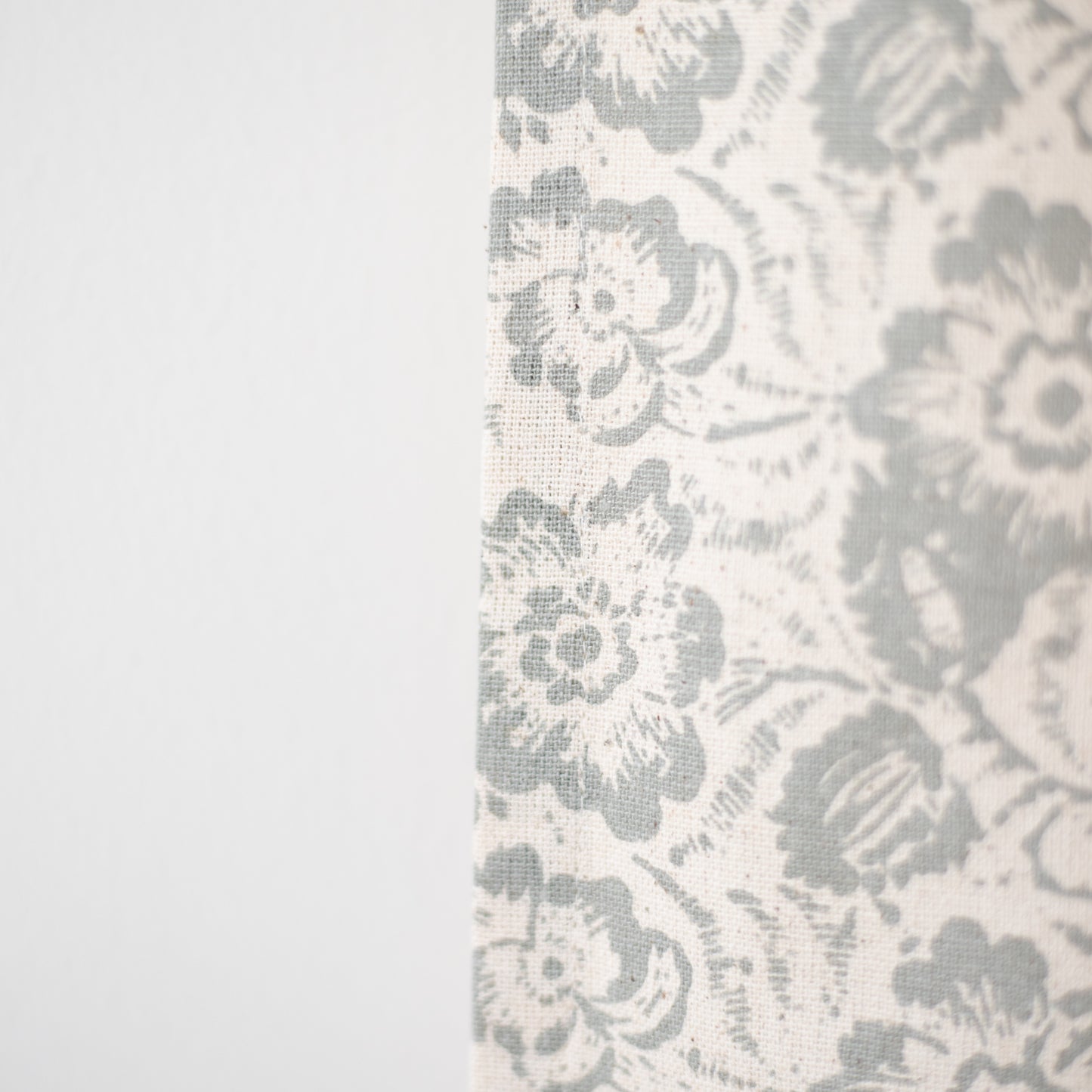 Cream curtain panel with gray floral and damask pattern in woven fabric texture.